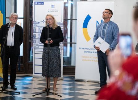 Fotografia. Wernisaż wystawy piękno jedności. hol główny willi decjusza. dyrektorka instytutu kultury willa decjusza dominika kasprowicz przemawia do mikrofonu, obok niej stoi jan piekło.